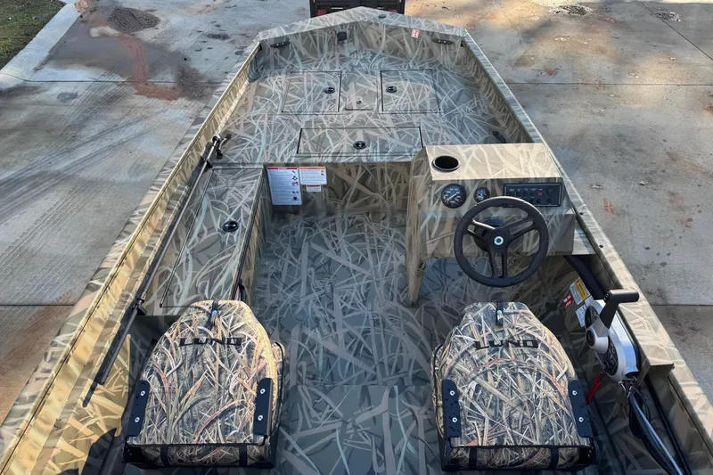 Slide: The Image of 2026 Lund 1760 Predator SC boat with camouflage design, featuring steering console and seating. - 5