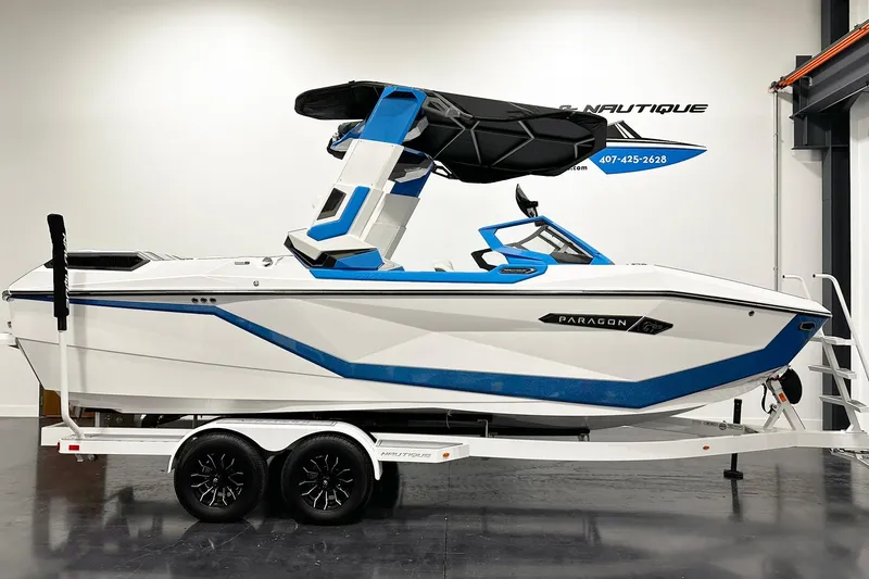 The Image of 2025 Nautique Super Air Nautique G23 Paragon boat in showroom, white and blue design. - 1