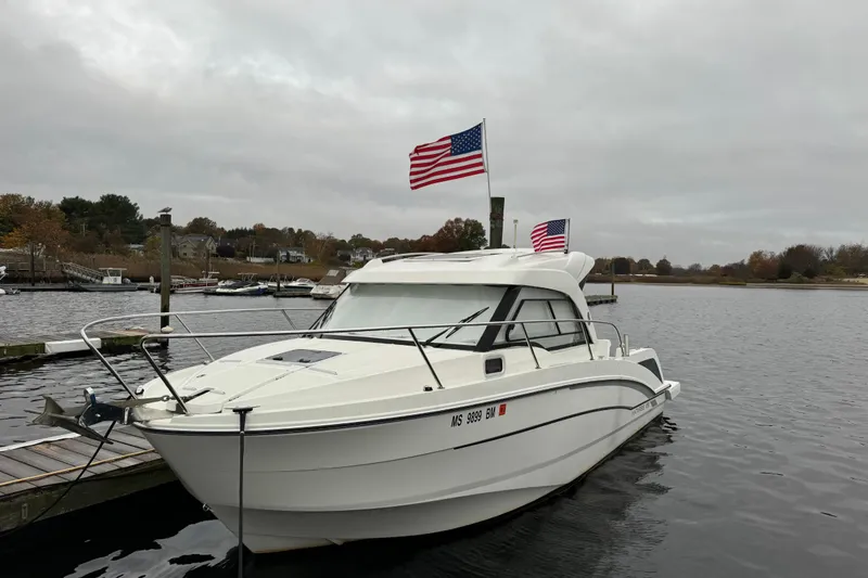 The Image of 2020 Beneteau Antares 8 boat docked with American flags, overcast sky. - 1