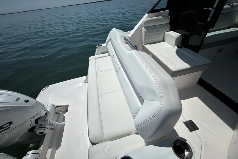 Slide: The Image of 2025 Regal 36 XO boat interior with white seating and outboard motor on calm water. - 12