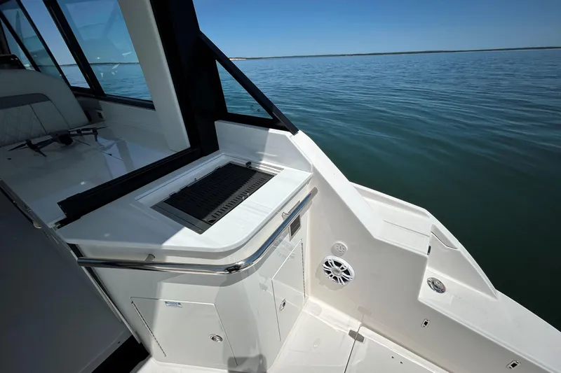 Slide: The Image of 2025 Regal 36 XO boat deck with grill, overlooking calm waters. - 15