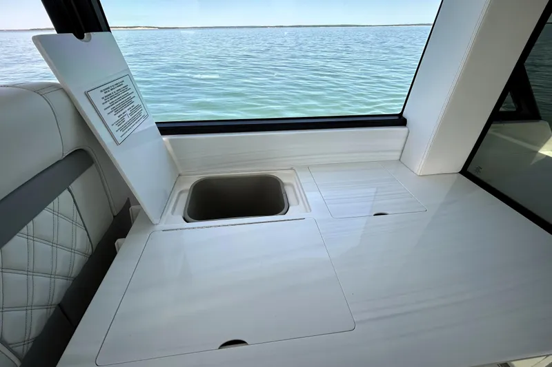 Slide: The Image of Interior of 2025 Regal 36 XO yacht with open storage compartment, overlooking serene water. - 21