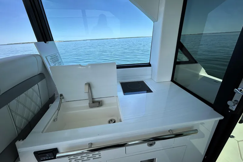 Slide: The Image of 2025 Regal 36 XO yacht interior with sink and cooktop, overlooking serene water. - 23