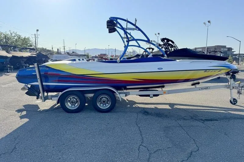 Slide: The Image of 2013 Caliber 1 230 Velocity boat on trailer, vibrant colors, parked outdoors. - 1