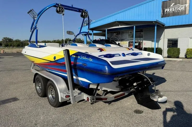 Slide: The Image of 2013 Caliber 1 230 Velocity boat on trailer, parked outside Prestige Water Sports. - 2