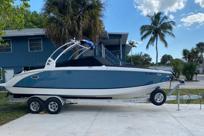 Slide: The Image of 2021 Cobalt R7 boat on trailer, parked near palm trees and a house. - 3