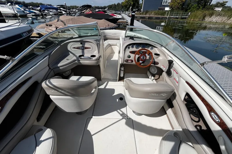 Slide: The Image of 2003 Sea Ray 240 Bow Rider interior with steering wheel and seating at a marina. - 6