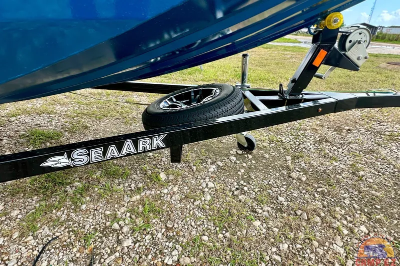 Slide: The Image of SeaArk C1074 Shadow 18TCC boat trailer, 2026 model, on gravel with spare tire. - 10