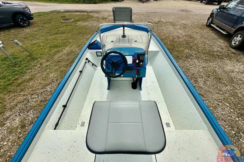 Slide: The Image of 2026 SeaArk C1074 Shadow 18TCC boat with blue trim, parked on gravel. - 15
