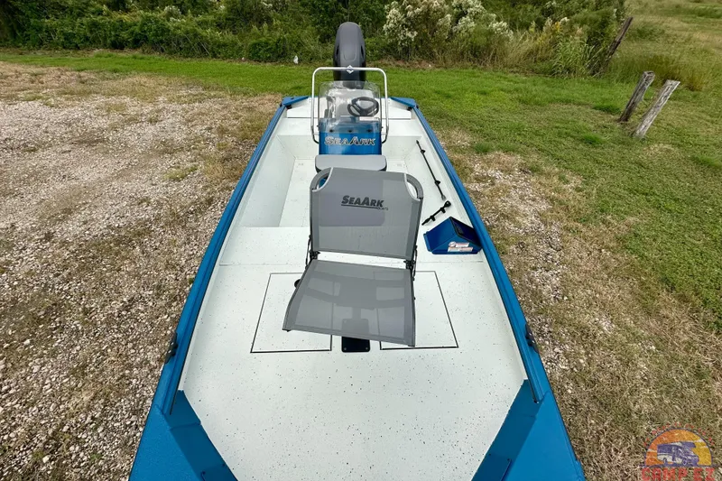 Slide: The Image of 2026 SeaArk C1074 Shadow 18TCC boat with seating, parked on grassy terrain. - 20