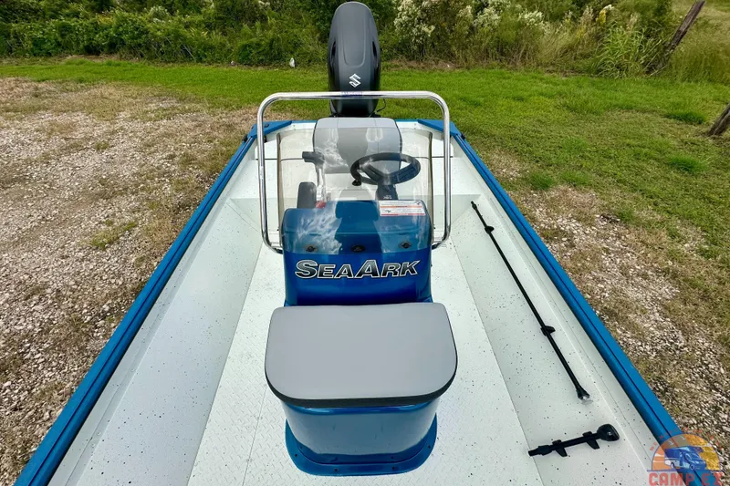 Slide: The Image of 2026 SeaArk C1074 Shadow 18TCC boat with console and seating, parked on gravel near grass. - 24