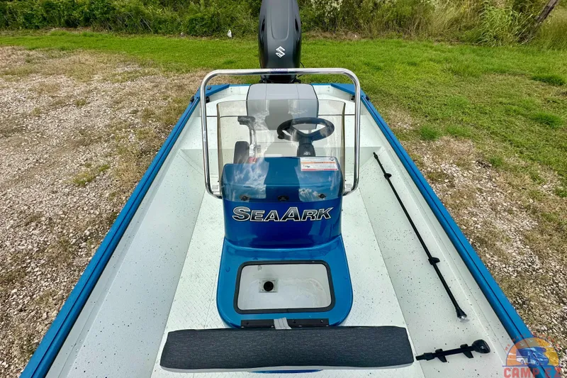 Slide: The Image of 2026 SeaArk C1074 Shadow 18TCC boat with blue console and steering wheel, parked on gravel. - 25