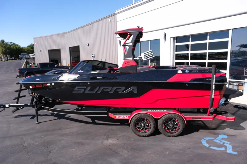 Slide: The Image of 2022 Supra SL boat in black and red on a trailer outside a building. - 3