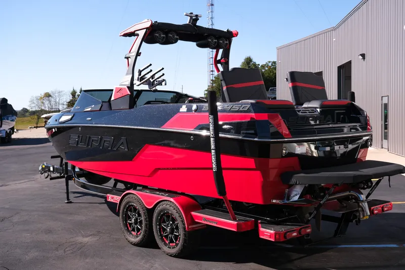 Slide: The Image of 2022 Supra SL boat in red and black, parked on a trailer outside a building. - 5