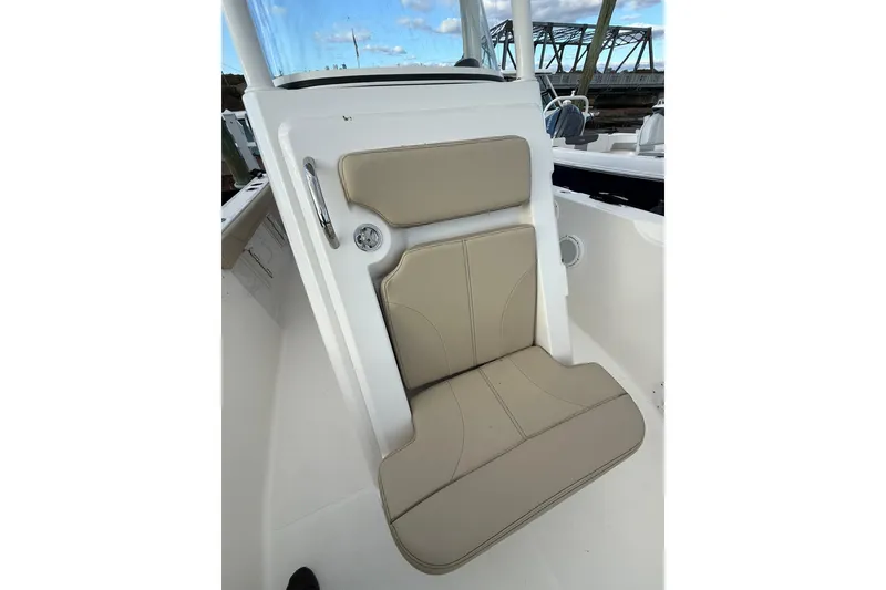 Slide: The Image of 2021 Pursuit C 238 Center Console boat with beige seating, docked near a bridge. - 17