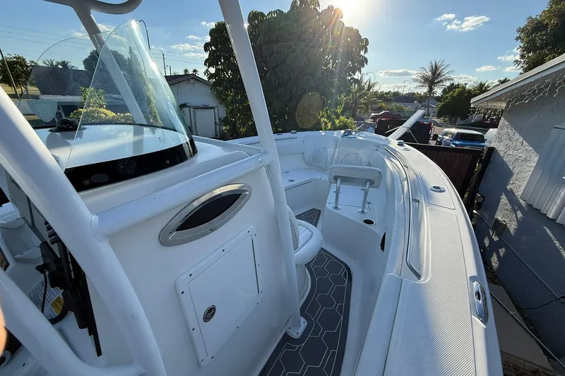 Slide: The Image of 2014 Sea Fox 256 Commander boat, white interior, sunny day, parked near trees and houses. - 51