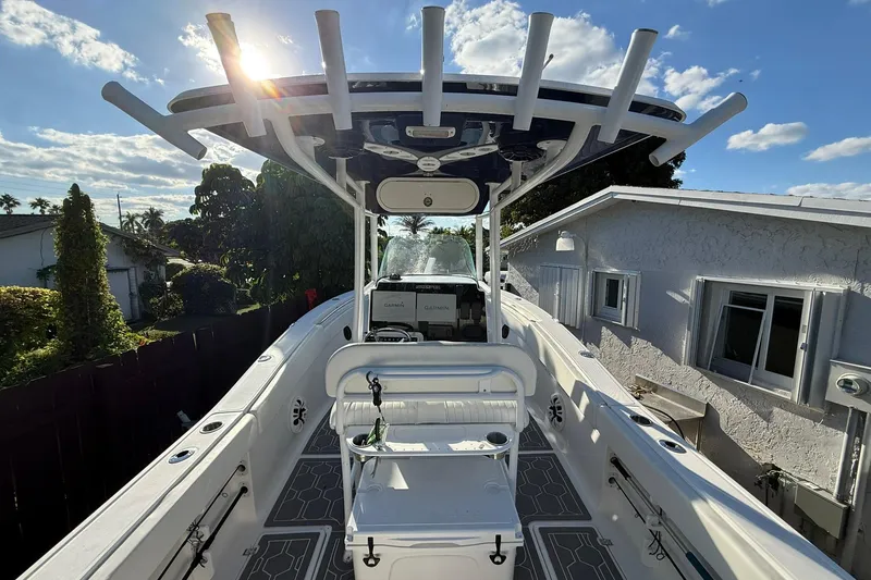 Slide: The Image of 2014 Sea Fox 256 Commander boat with T-top, docked near a house under a sunny sky. - 9