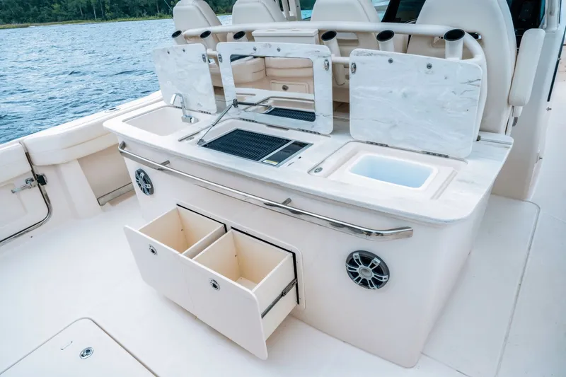 Slide: The Image of Grady-White Canyon 386 2027: Sleek outdoor kitchen with sink, grill, and storage, set on calm waters. - 3