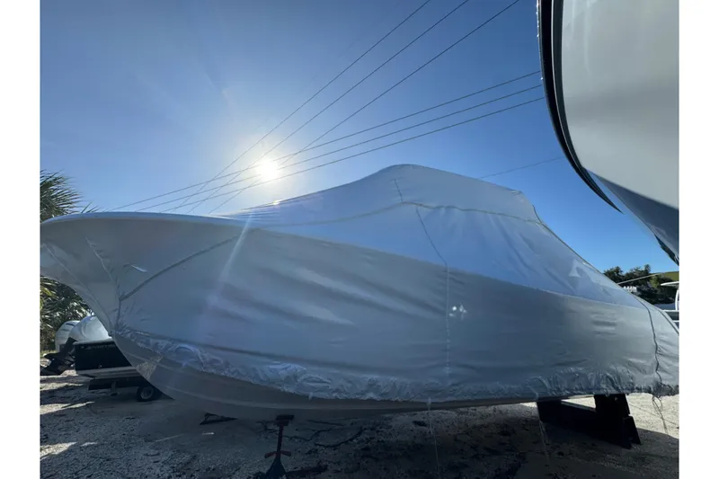 Slide: The Image of Covered 2026 Sportsman Open 232 Center Console boat under bright sun. - 12