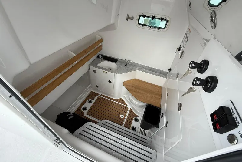 Slide: The Image of Interior of 2026 Everglades 315 Center Console boat, featuring a compact bathroom with sink and toilet. - 17