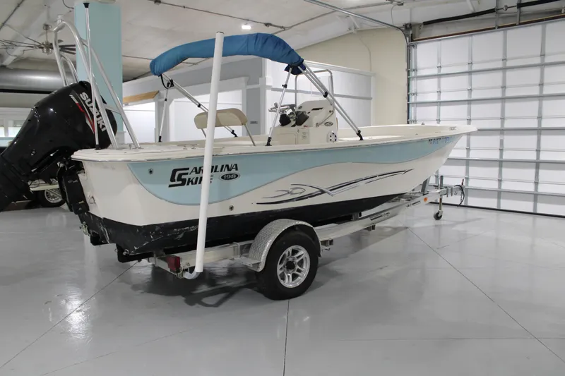 The Image of 2014 Carolina Skiff 198 DLV boat with Suzuki outboard motor in a garage. - 0