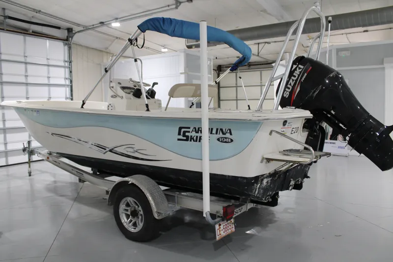 Slide: The Image of 2014 Carolina Skiff 198 DLV boat with Suzuki outboard motor in a garage. - 3