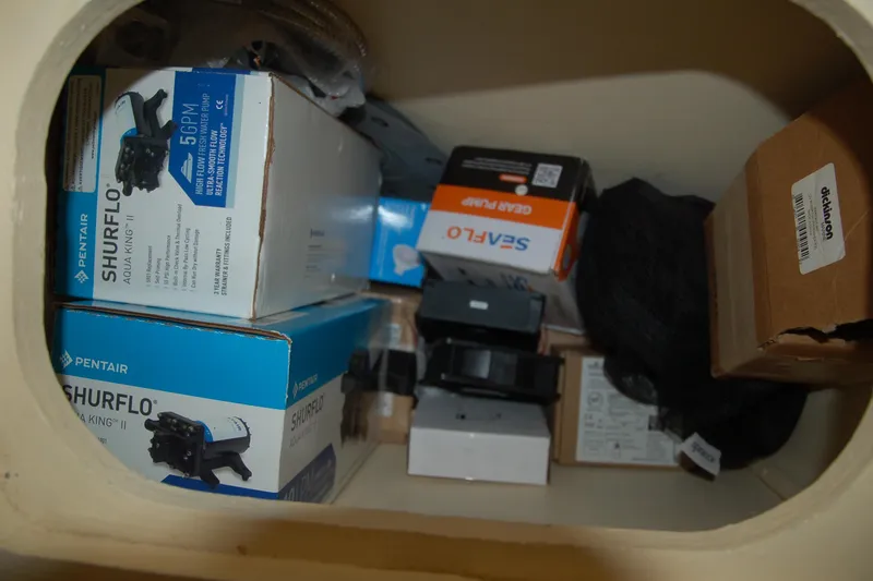 Slide: The Image of Storage compartment with various boxes, including Pentair Shurflo pumps, in a Custom Sprague 2006 model. - 109