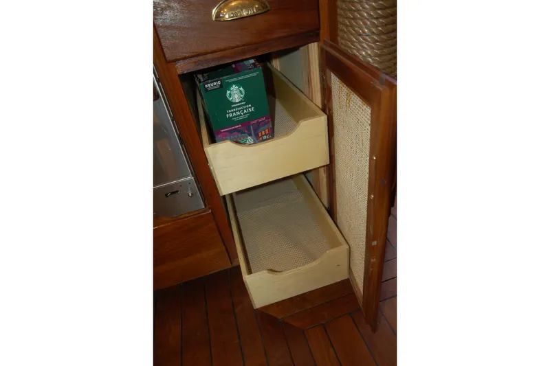 Slide: The Image of Wooden cabinet with pull-out shelves, containing a box of Starbucks French Roast coffee. - 115