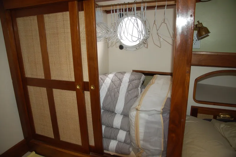 Slide: The Image of Wooden closet with hangers and bedding in a 2006 Custom Sprague boat cabin. - 141