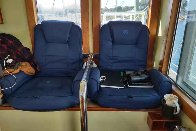 Slide: The Image of Two blue cushioned seats in a boat cabin with binoculars and a mug nearby. - 17