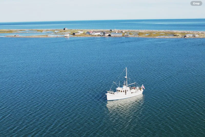 Slide: The Image of A 2006 Custom Sprague boat on calm blue waters near a small coastal settlement. - 5