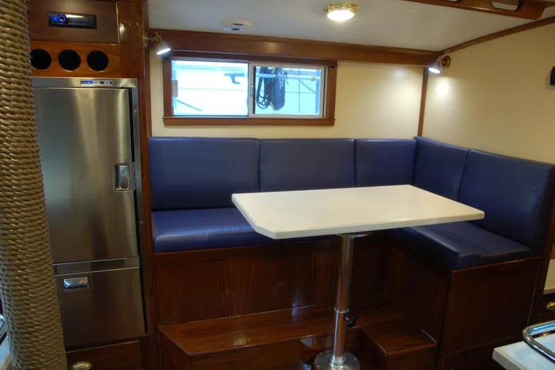 Slide: The Image of Cozy boat interior with blue seating, white table, and stainless steel fridge, Custom Sprague 2006. - 50