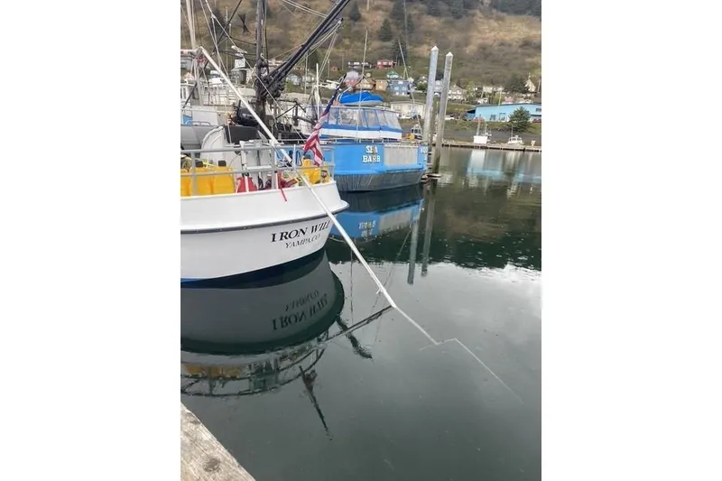 Slide: The Image of Boats docked in a calm harbor, reflecting in the water, with a mountainous backdrop. - 6