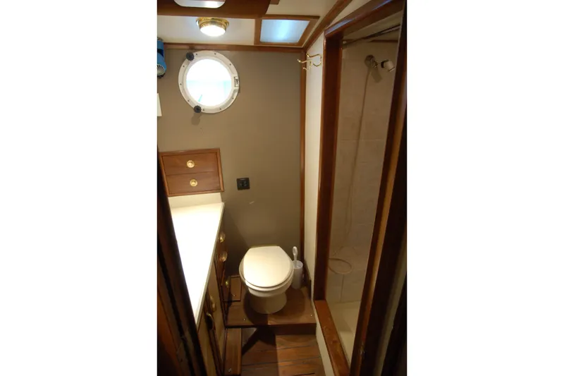 Slide: The Image of Compact boat bathroom with porthole, shower, and wooden cabinetry, Custom Sprague 2006 model. - 62