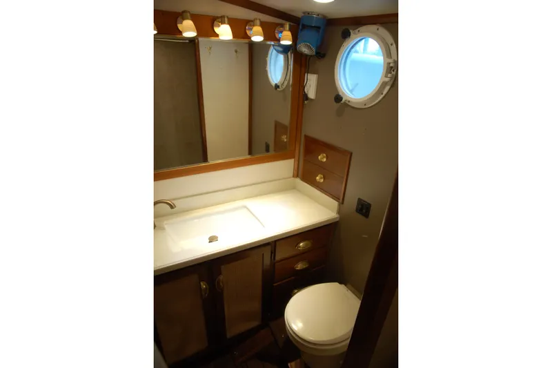 Slide: The Image of Compact bathroom with porthole window, wooden cabinets, and modern lighting in a 2006 Custom Sprague. - 63