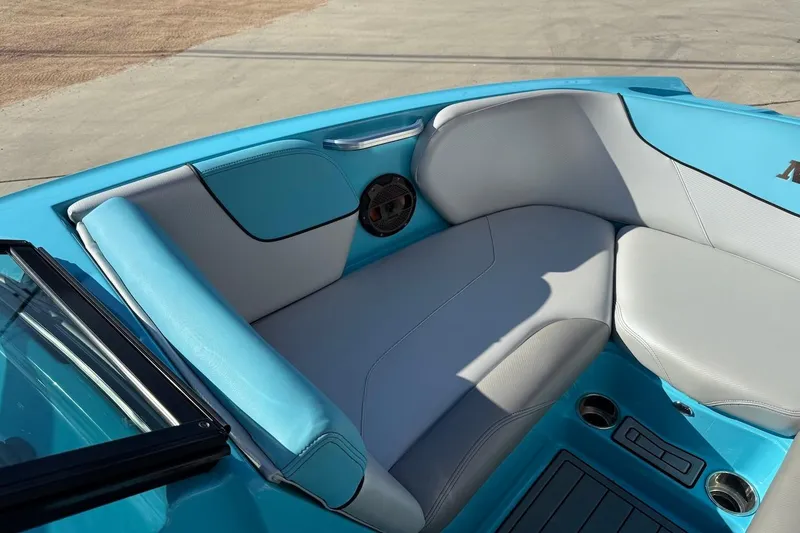 Slide: The Image of 2018 MasterCraft NXT22 boat interior with blue and gray seating, cup holders, and speaker. - 12