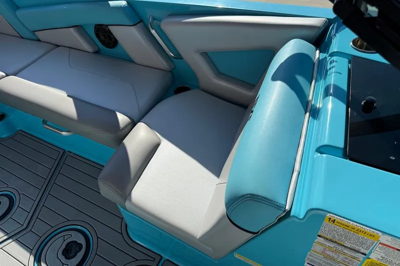 Slide: The Image of 2018 MasterCraft NXT22 interior with blue and gray seating, cup holders, and capacity label. - 15