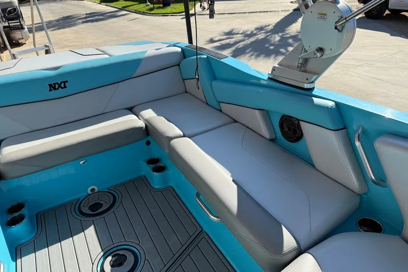 Slide: The Image of 2018 MasterCraft NXT22 boat interior with blue and gray seating, cup holders, and speaker. - 16