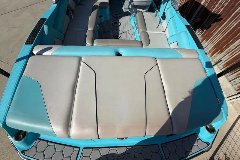 Slide: The Image of 2018 MasterCraft NXT22 boat interior with blue and gray seating, docked outdoors. - 5