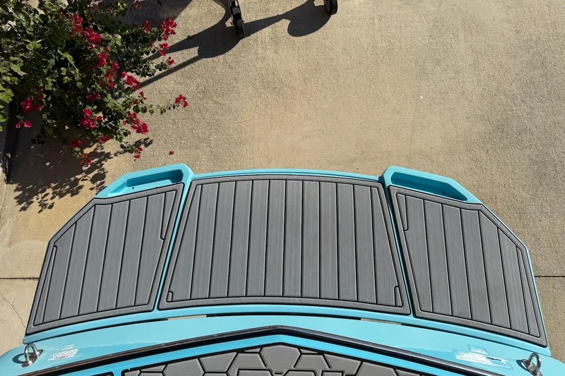 Slide: The Image of 2018 MasterCraft NXT22 boat with gray deck, blue accents, and nearby red flowers. - 6