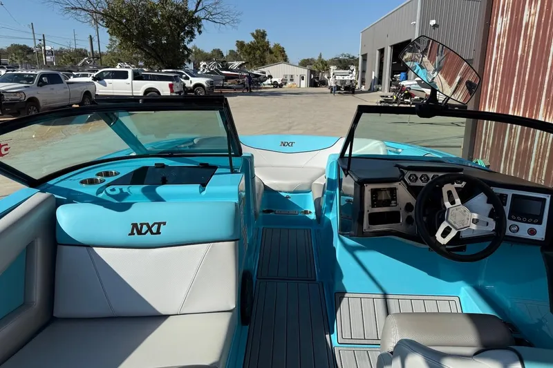 Slide: The Image of 2018 MasterCraft NXT22 boat interior with blue and white seating, steering wheel, and dashboard. - 7