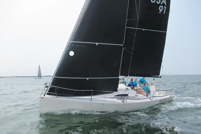 Slide: The Image of 2017 J Boats J/88 sailing with crew, black sails, on open water. - 3