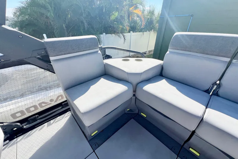 Slide: The Image of 2023 Sea-Doo Switch Cruise 21 interior seating with cup holders, surrounded by lush greenery. - 12