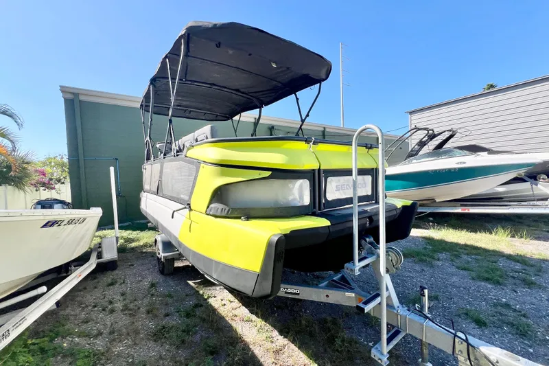 Slide: The Image of 2023 Sea-Doo Switch Cruise 21 pontoon boat on trailer, parked outdoors. - 2