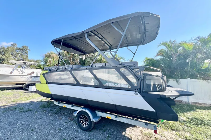 Slide: The Image of 2023 Sea-Doo Switch Cruise 21 pontoon boat with canopy on a trailer, parked outdoors. - 6