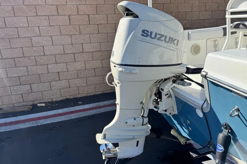 Slide: The Image of Clearwater 2000 C/C 2021 boat with Suzuki outboard motor, parked near brick wall. - 7