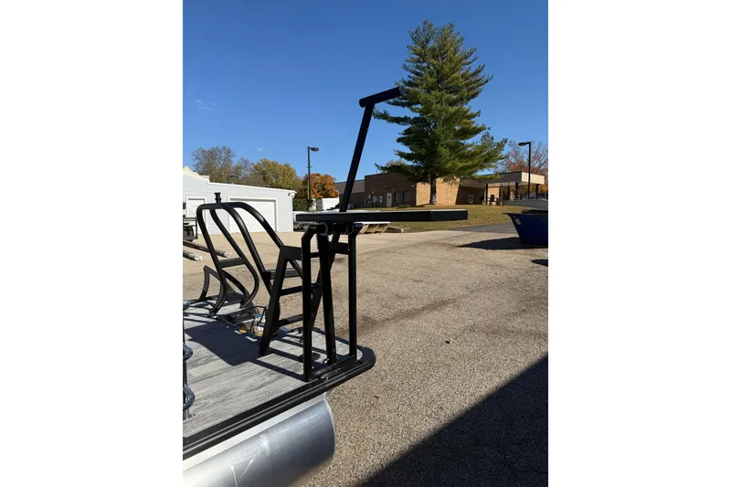 Slide: The Image of 2026 Bentley Pontoons Legacy 243 Swingback, docked, with sleek black railings under clear blue sky. - 13