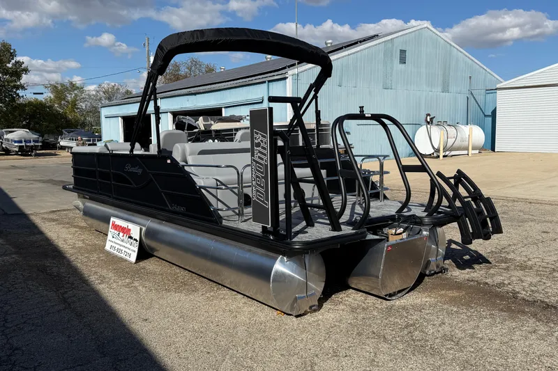 Slide: The Image of 2026 Bentley Pontoons Legacy 243 Swingback in a boatyard under a partly cloudy sky. - 2