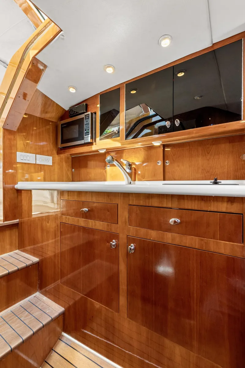 Slide: The Image of Luxurious 2009 Hinckley Runabout 38 yacht interior with polished wood cabinetry and modern amenities. - 12