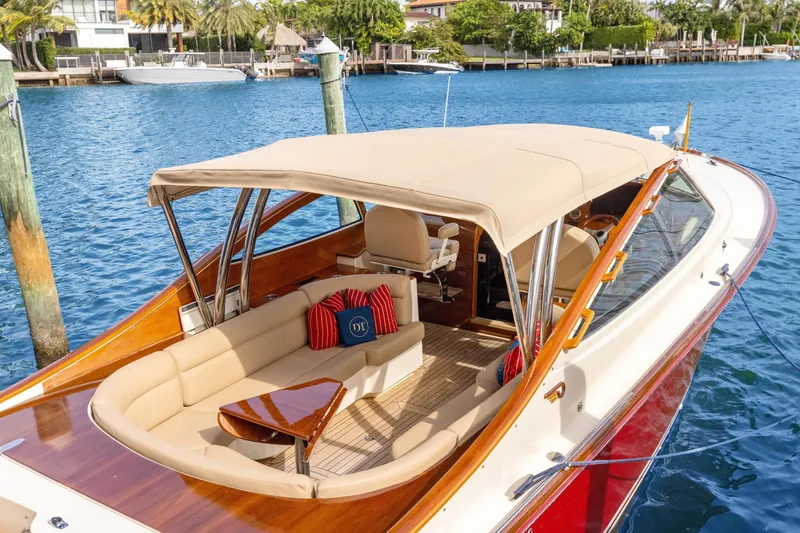 Slide: The Image of 2009 Hinckley Runabout 38 with beige canopy, docked on a sunny waterfront. - 6